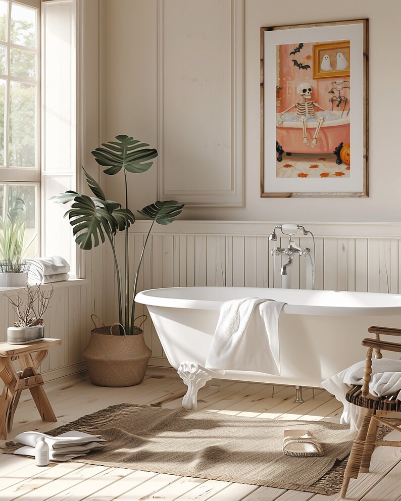 K&ouml;nnte beinhalten: Ein Badezimmer mit einer wei&szlig;en Badewanne mit L&ouml;wenf&uuml;&szlig;en, einem gerahmten Kunstwerk und einer gro&szlig;en Topfpflanze. Das Kunstwerk zeigt ein Skelett in einer Badewanne. Ein gewebter Teppich und ein Holzschemel erg&auml;nzen die Einrichtung. Der Raum hat eine neutrale Farbpalette.