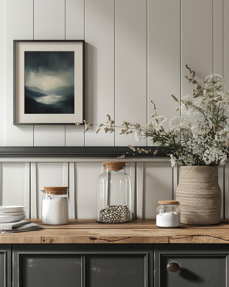 May include: Three glass jars with wooden lids on a wooden countertop. The jars are filled with white powder, white beans, and white powder. A vase with white flowers sits on the counter. The countertop is in front of a white paneled wall.