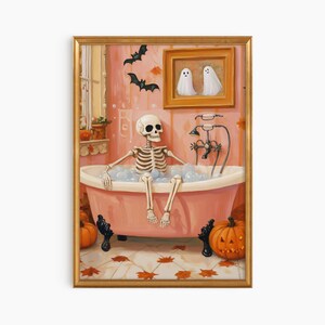 K&ouml;nnte beinhalten: Ein gerahmter Halloween-Print zeigt ein Skelett, das sich in einer rosa Badewanne mit Blasen entspannt. Das Badezimmer ist mit K&uuml;rbissen, Flederm&auml;usen und einem gerahmten Bild von zwei Geistern dekoriert. Das Kunstwerk hat einen goldenen Rahmen.