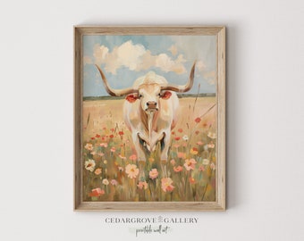 May include: A framed art print featuring a longhorn in a field of wildflowers. The artwork has a rustic, painterly style with a neutral color palette of beige, cream, and soft pinks. The sky is a light blue with fluffy white clouds.