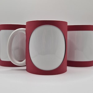 Op de afbeelding: Drie witte keramische mokken met een rode accentkleur. De mokken hebben een wit interieur en een rode band rond de boven- en onderkant. Eén mok heeft een rood frame rond het witte midden. De mokken hebben witte handvatten.