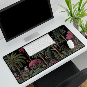 May include: A black rectangular mouse pad featuring a jungle scene with palm trees, monkeys, and pink flowers. A white keyboard and mouse sit on the pad, next to a computer monitor. The pad is on a white desk.