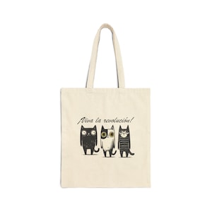 May include: A beige tote bag with a black and white illustration of three cats with the text "Viva la revolucion!" printed on the front.