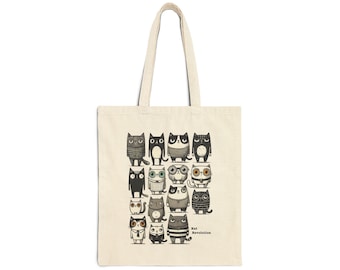 Puede incluir: Una bolsa de tela beige con una ilustración en blanco y negro de gatos con gafas y jerséis. El texto "Kat Revolution" está impreso en la parte inferior de la bolsa.