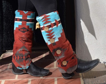 Puede incluir: Un par de polainas de color rojo, azul y turquesa con botones marrones. Las polainas se llevan sobre pantalones negros y botas marrones.