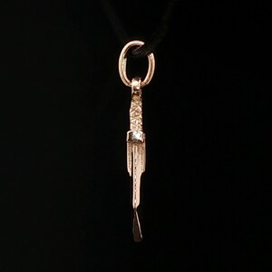 Antique bronze Cloud Strife sword charm from FFVII Final Fantasy gamer jewelry. Small FF7 Buster Sword charm in antique bronze Final Fantasy Cloud Strife pendant. Close up of small Buster Sword pendant in bronze FF7 inspired cosplay accessory. Mini Final Fantasy sword charm in bronze Cloud Strife cosplay gift