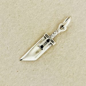 Small FF7 Buster Sword charm in sterling silver Final Fantasy Cloud Strife pendant. Close up of small Buster Sword pendant in silver FF7 inspired cosplay accessory. Mini Final Fantasy sword charm in sterling silver Cloud Strife cosplay gift.