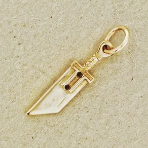Antique bronze Cloud Strife sword charm from FFVII Final Fantasy gamer jewelry. Small FF7 Buster Sword charm in antique bronze Final Fantasy Cloud Strife pendant. Close up of small Buster Sword pendant in bronze FF7 inspired cosplay accessory. Mini Final Fantasy sword charm in bronze Cloud Strife cosplay gift.
