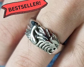 May include: A silver-toned metal ring featuring a sculpted lion head design with detailed mane textures. A red banner graphic with black text reading BESTSELLER! is positioned above the ring, which is worn on a finger.