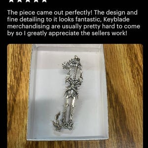 a silver keychain in a white box on a wooden surface.