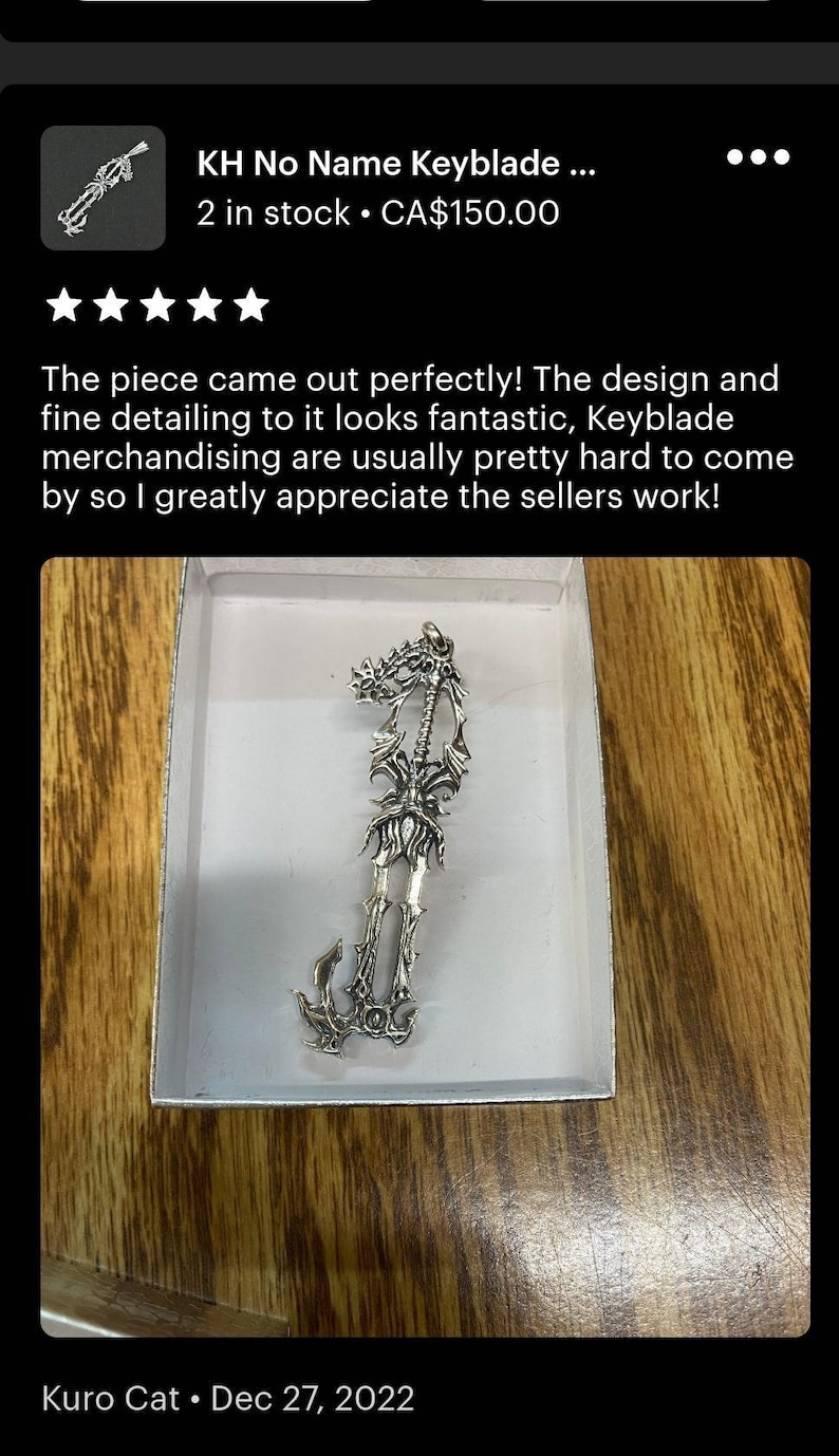 a silver keychain in a white box on a wooden surface.