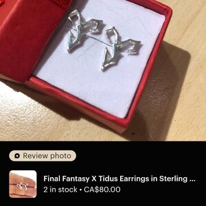 a pair of earrings in a red box, which appears to be a gift box. The earrings are described as "Final Fantasy X Tidus Earrings in Sterling" and are in perfect condition. The earrings are in stock and cost $80.00. The image also includes a review rating of 4 stars, indicating that the earrings are in excellent condition and the seller is very happy with the product.