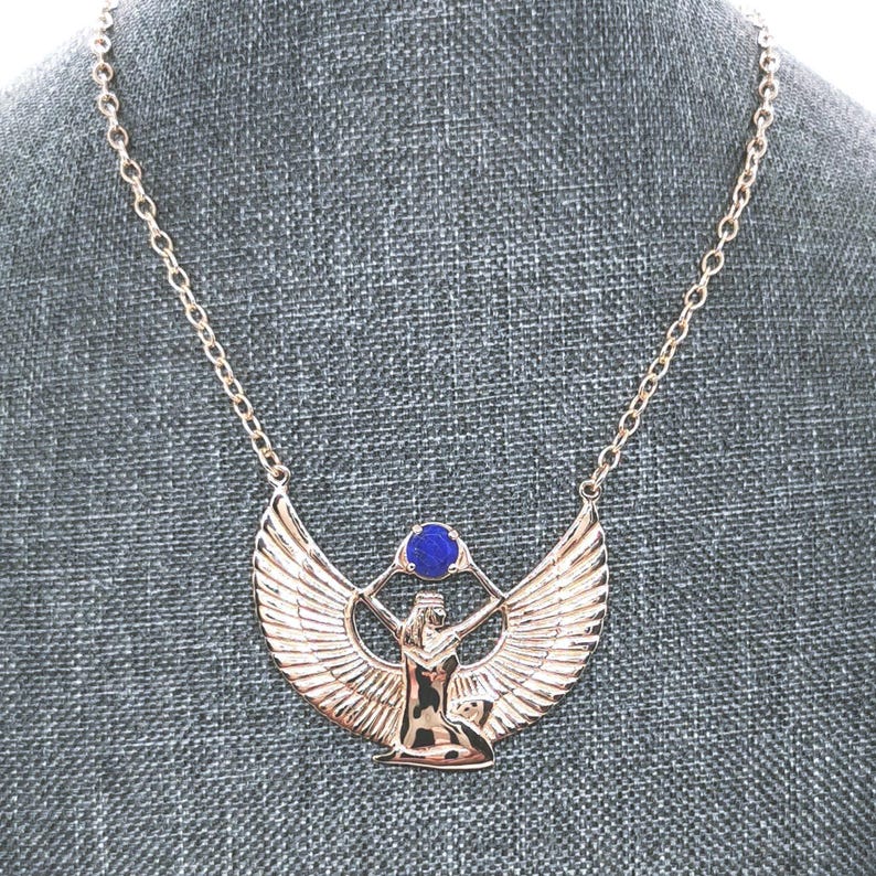 Close-up of Isis necklace in bronze with wings and lapis gemstone. Egyptian goddess Isis pendant with lapis lazuli ancient bronze necklace