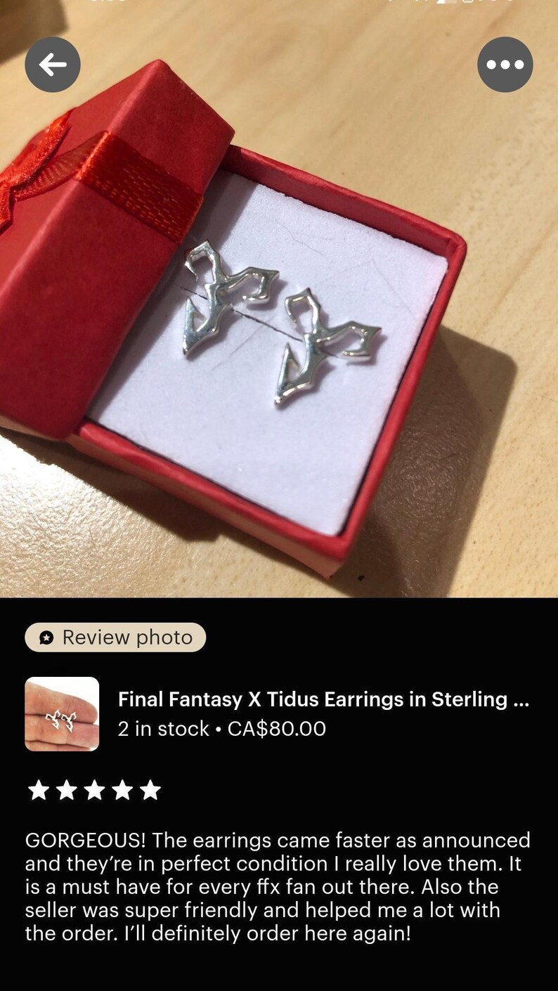 a pair of earrings in a red box, which appears to be a gift box. The earrings are described as "Final Fantasy X Tidus Earrings in Sterling" and are in perfect condition. The earrings are in stock and cost $80.00. The image also includes a review rating of 4 stars, indicating that the earrings are in excellent condition and the seller is very happy with the product.