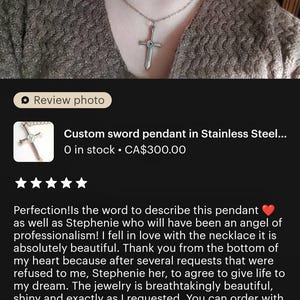 The image is a close-up of a woman's face wearing a pendant necklace with a cross pendant. The pendant is described as a custom sword pendant in stainless steel, and it is shown in stock at $300.00. The image also includes a review rating of 5 stars, indicating that the necklace is well-received by customers.