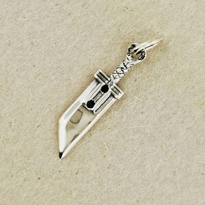 Small FF7 Buster Sword charm in sterling silver Final Fantasy Cloud Strife pendant. Close up of small Buster Sword pendant in silver FF7 inspired cosplay accessory. Mini Final Fantasy sword charm in sterling silver Cloud Strife cosplay gift.