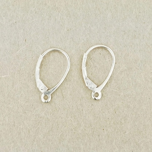 May include: Two silver earring clasps. Each clasp features a teardrop-shaped loop and a hinged lever with a small hole at the base. These clasps are designed for securing earrings.