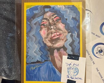 May include: An art print featuring a portrait of a person with blue hair and a blue top, set against a yellow and brown background. The print is labeled "Sage print 5x7in" and "The Moon Sees Me".