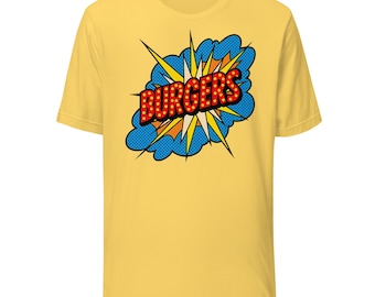 May include: Yellow t-shirt featuring a comic book style graphic. The graphic includes the word "BURGERS" in red letters with yellow highlights, set against a blue and orange burst design. The shirt is a short-sleeved crew neck.
