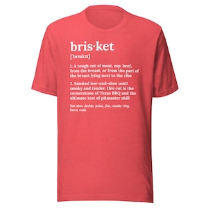 Può includere: T-shirt rossa con la parola "bris-ket" e la sua pronuncia in testo bianco. La maglietta presenta una definizione di brisket, descrivendolo come un taglio di carne duro, spesso manzo, e la pietra angolare del barbecue texano.