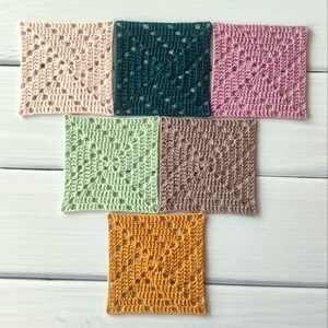 May include: A collection of six square crochet motifs arranged in a T-shape. The squares feature a classic granny square pattern with openwork stitches. The colours include pale pink, dark teal, mauve, light green, dusty rose, and mustard yellow.