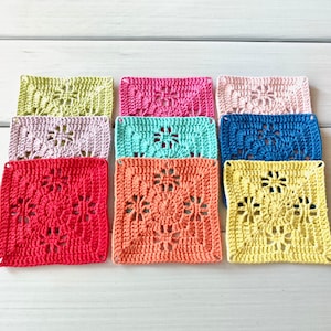 May include: A collection of colorful, square crochet pieces in various shades including pink, blue, yellow, and orange. Each piece features a detailed floral design in the center, with an openwork pattern.