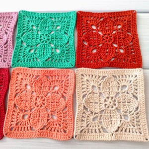 May include: Close-up of several colorful, square crochet pieces. The pieces are in shades of pink, green, red, peach, and beige. Each square features a floral design in the center. The crochet work is detailed and intricate.