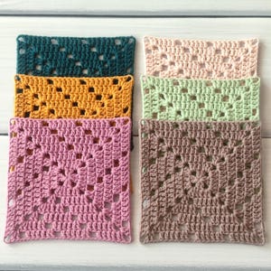May include: A collection of six square crochet granny squares in various solid colours including dark teal, mustard yellow, dusty pink, pale peach, light sage green, and taupe. Each square features a classic openwork pattern with a central motif.