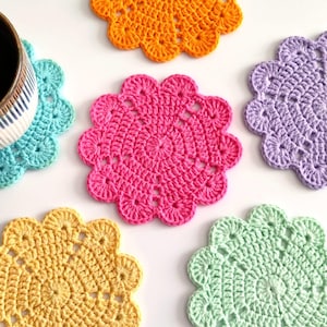 May include: A collection of six round, crocheted coasters in vibrant colors including orange, pink, lavender, yellow, mint green, and turquoise, each featuring a scalloped edge and a central circular pattern with openwork details.