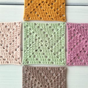 May include: Five square crochet motifs arranged in a cross pattern. The centre square is light green, surrounded by a mustard yellow square at the top, a light pink square on the left, a mauve square on the right, and a brown square at the bottom.