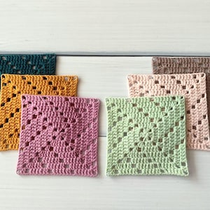 May include: A set of six square crochet coasters featuring a classic granny square pattern. The coasters are crafted in various solid colours including dark teal, mustard yellow, dusty pink, light green, pale peach, and a muted brown shade.