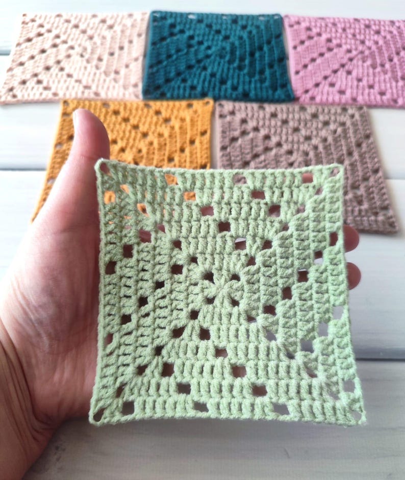 May include: A collection of six square crochet motifs in various solid colours including light green, mustard yellow, teal, light pink, dusty rose, and beige. Each piece features a central star-like pattern surrounded by openwork stitches.