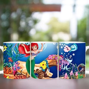 Puede incluir: Taza de cer&aacute;mica blanca con una colorida ilustraci&oacute;n de Ariel, Flounder y Sebasti&aacute;n de La Sirenita. El dise&ntilde;o incluye escenas submarinas con corales, peces y burbujas. La taza tiene un asa blanca.