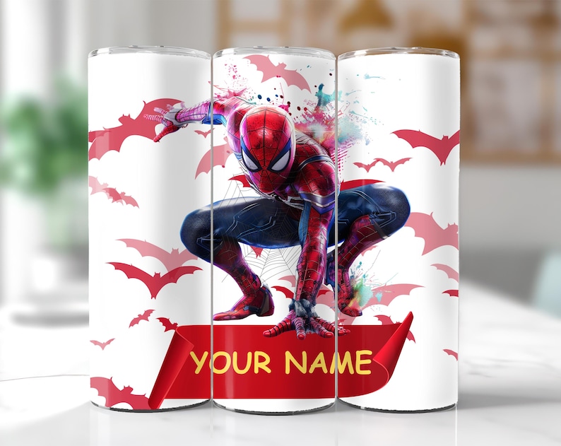 Pode incluir: Um copo branco com o Homem-Aranha em uma pose din&acirc;mica, cercado por silhuetas de morcegos vermelhos. O super-her&oacute;i &eacute; retratado em seu traje cl&aacute;ssico vermelho e azul. Uma faixa vermelha na parte inferior exibe o texto "YOUR NAME" em amarelo.