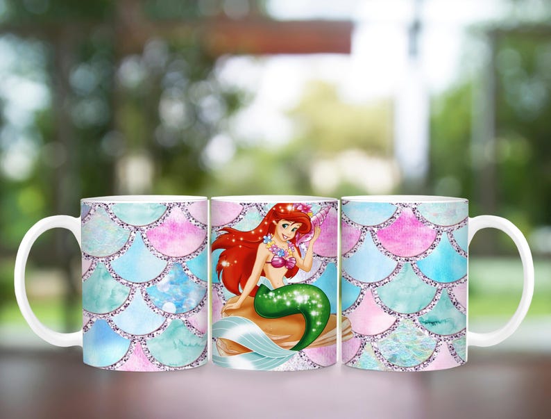 Puede incluir: Taza de cer&aacute;mica blanca con dise&ntilde;o de sirena. La taza presenta una ilustraci&oacute;n de sirena con cabello rojo y cola verde. El fondo tiene un patr&oacute;n de escamas en tonos de azul, rosa y verde azulado.