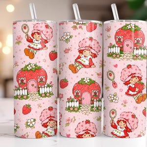 Peut inclure: Gobelet rose avec un motif répété d'une fille de dessin animé avec un chapeau de fraise, des fraises et une maison en forme de fraise. Le motif comprend des fleurs blanches et une clôture blanche. Le gobelet a une paille transparente.