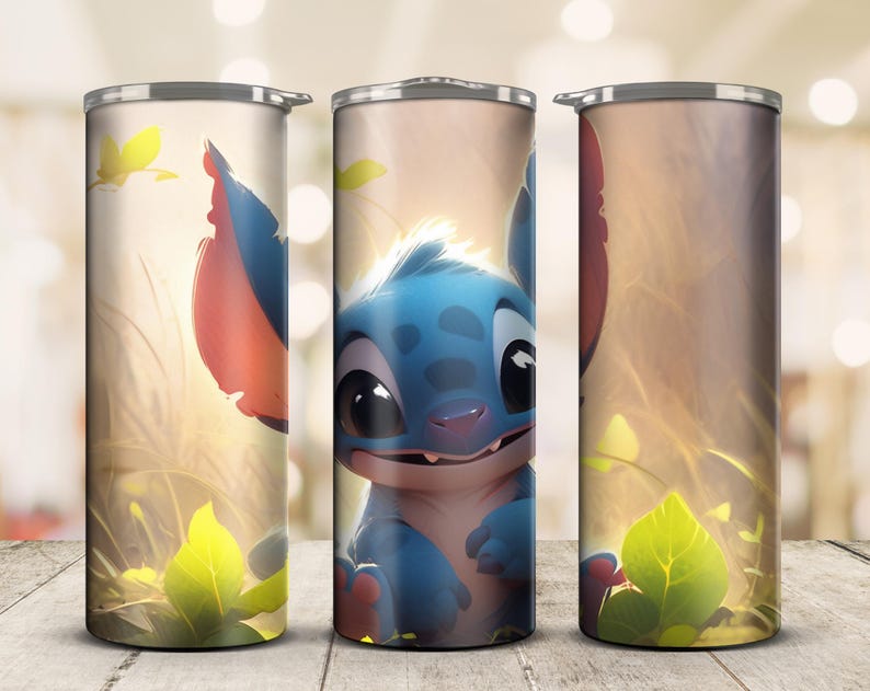 May include: A stainless steel tumbler featuring a cartoon character with blue fur, large black eyes, and large ears. The design includes a light background with yellow and green foliage. The tumbler is cylindrical and has a silver lid.