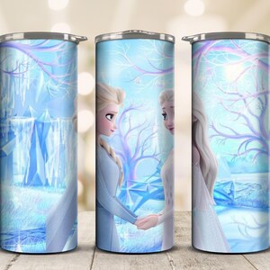 May include: A stainless steel tumbler featuring a winter scene with two animated female characters in light blue dresses, holding hands. The design includes a snowy landscape with trees and ice formations, all in shades of blue and white.