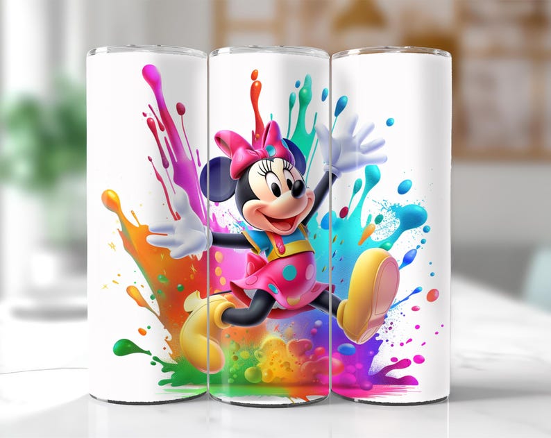 Puede incluir: Vaso blanco con Minnie Mouse con vestido y lazo rosa, rodeada de salpicaduras de pintura coloridas. El dise&ntilde;o incluye acentos amarillos, azules, verdes, naranjas y morados, creando un aspecto vibrante.