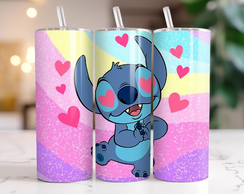 Puede incluir: Tres vasos de acero inoxidable con pajitas. Cada vaso presenta un dise&ntilde;o colorido con un personaje de dibujos animados, Stitch, rodeado de corazones rosas. El fondo tiene un patr&oacute;n de arco&iacute;ris pastel.