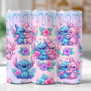 May include: Three stainless steel tumblers with a repeating pattern of blue and pink cartoon characters, flowers, and hearts. The background is a light pink with a blue dripping design at the top. The tumblers are decorated with a cute, colorful design.
