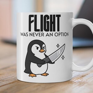 May include: White ceramic mug featuring a cartoon penguin holding a knife. The mug has the text "FLIGHT WAS NEVER AN OPTION" in black block letters. The penguin is black, white, and orange, with a stern expression.