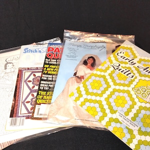 May include: A collection of quilting pattern books, including "Early American Quilts" with a yellow and green geometric design, and "Mange Murphys" featuring a bride. Other books include "Stitch n' Spa" and "Lady's Circle Patchwork Quilts".