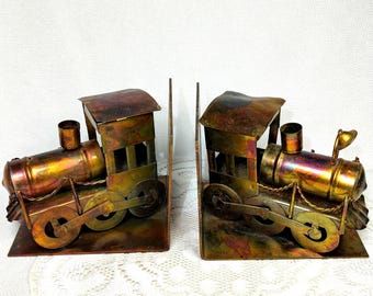Suportes de livros vintage em metal, estilo locomotiva, com pátina e manchas, típicos do estilo meados do século.