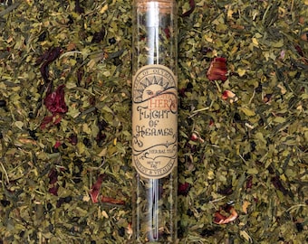 Może przedstawiać: Szklana probówka wypełniona luźnymi zielonymi, brązowymi i czerwonymi liśćmi herbaty ziołowej. Etykieta na probówce głosi "Property of Olympus Herbal Flight of Hermes Herbal Tea Net Wt 12g Energy & Vitality".