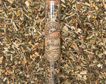 Może przedstawiać: Szklana probówka wypełniona suszonymi ziołami z etykietą z napisem "Property of Olympus Herbal Tears of Apollo Herbal Tea Net Wt 1 oz Healing & Immunity".