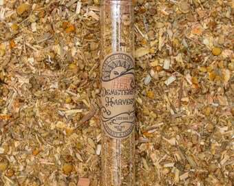 Może przedstawiać: Szklana probówka wypełniona suszonymi ziołami, z etykietą "Proper Herbs Demeter's Harvest Herbal Tea Net Wt 1.25 oz Detoxify & Cleanse"