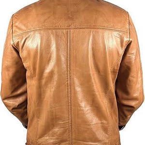 May include: A tan leather jacket with a classic design. The jacket features a collared neckline, a button-down front, and a tailored fit. The back of the jacket has a yoke detail and vertical seam. The jacket is made of a smooth, textured leather.