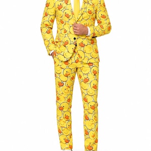 Könnte beinhalten: Ein leuchtend gelber Anzug mit einem durchgehenden Muster aus Cartoon-Quietscheentchen mit orangefarbenen Schnäbeln. Das Set besteht aus einem einreihigen Blazer mit fallendem Revers, einer passenden Hose, einem weißen Hemd und einer gelben Krawatte.