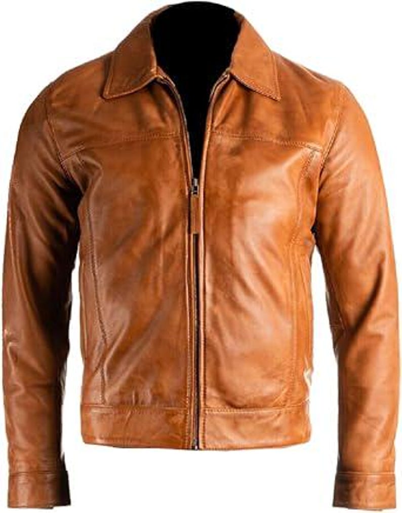 May include: A tan leather jacket featuring a collared neckline and a full-length zip. The jacket has long sleeves and a tailored fit, with visible stitching details. The leather has a slightly distressed appearance.